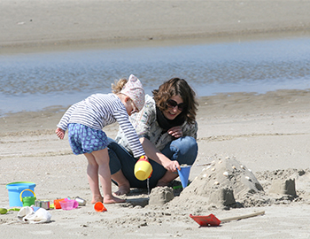 Mor og barn bygger sandslotte på stranden